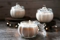 Three glass jars with white candle contents on a wooden surface.