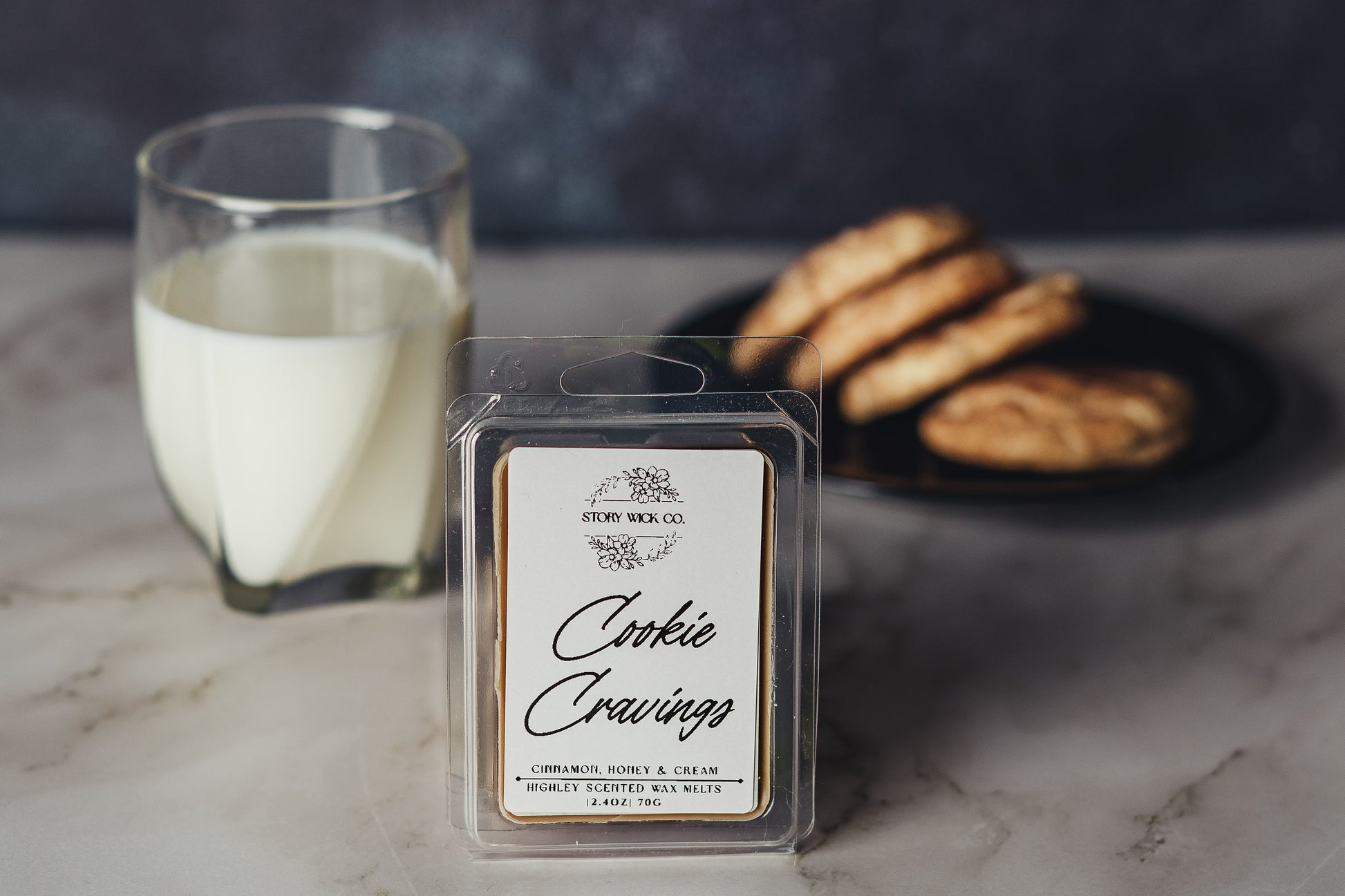 Packaged cookie-scented wax melt with a glass of milk and cookies on a marble surface
