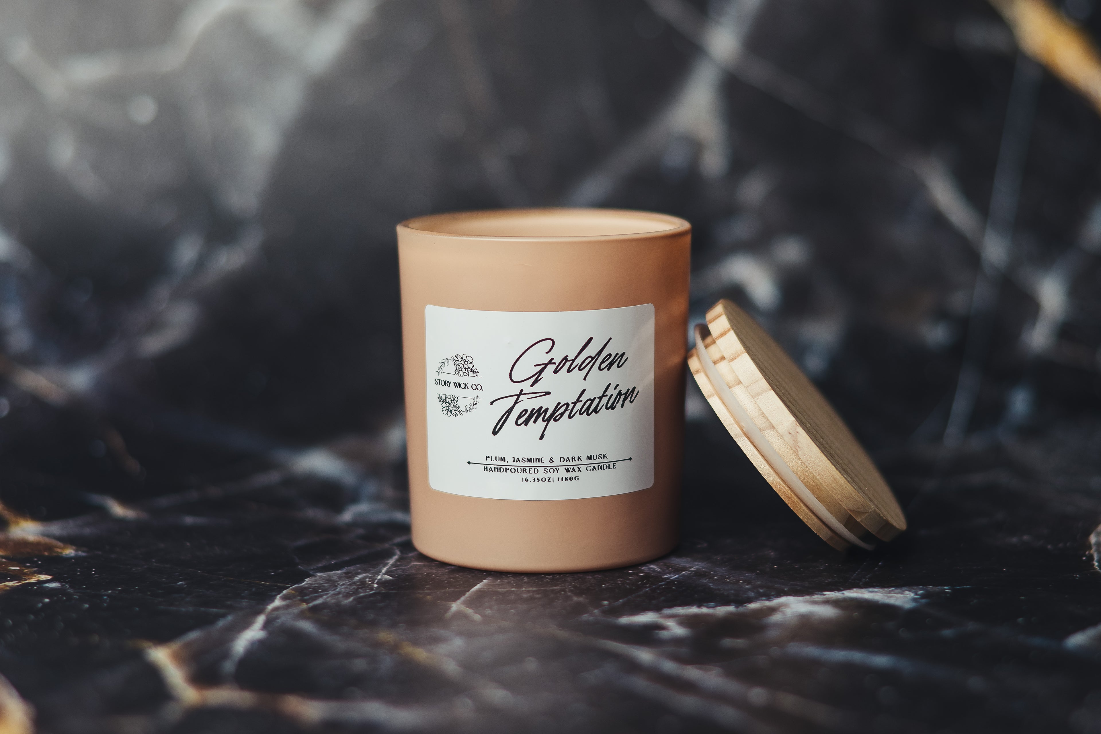 Candle with a wooden lid on a dark marble surface