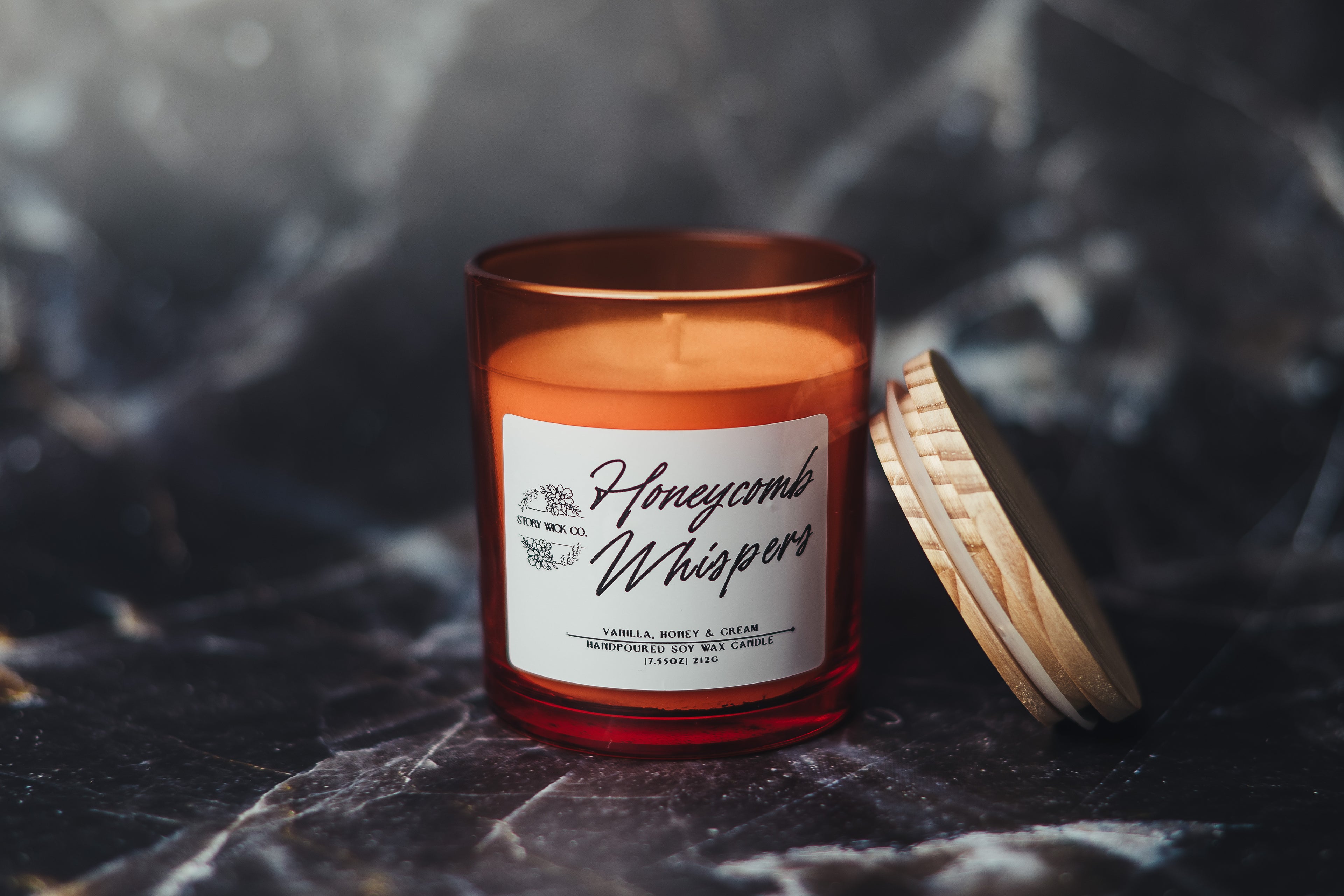 Candle with a label on a dark textured surface.
