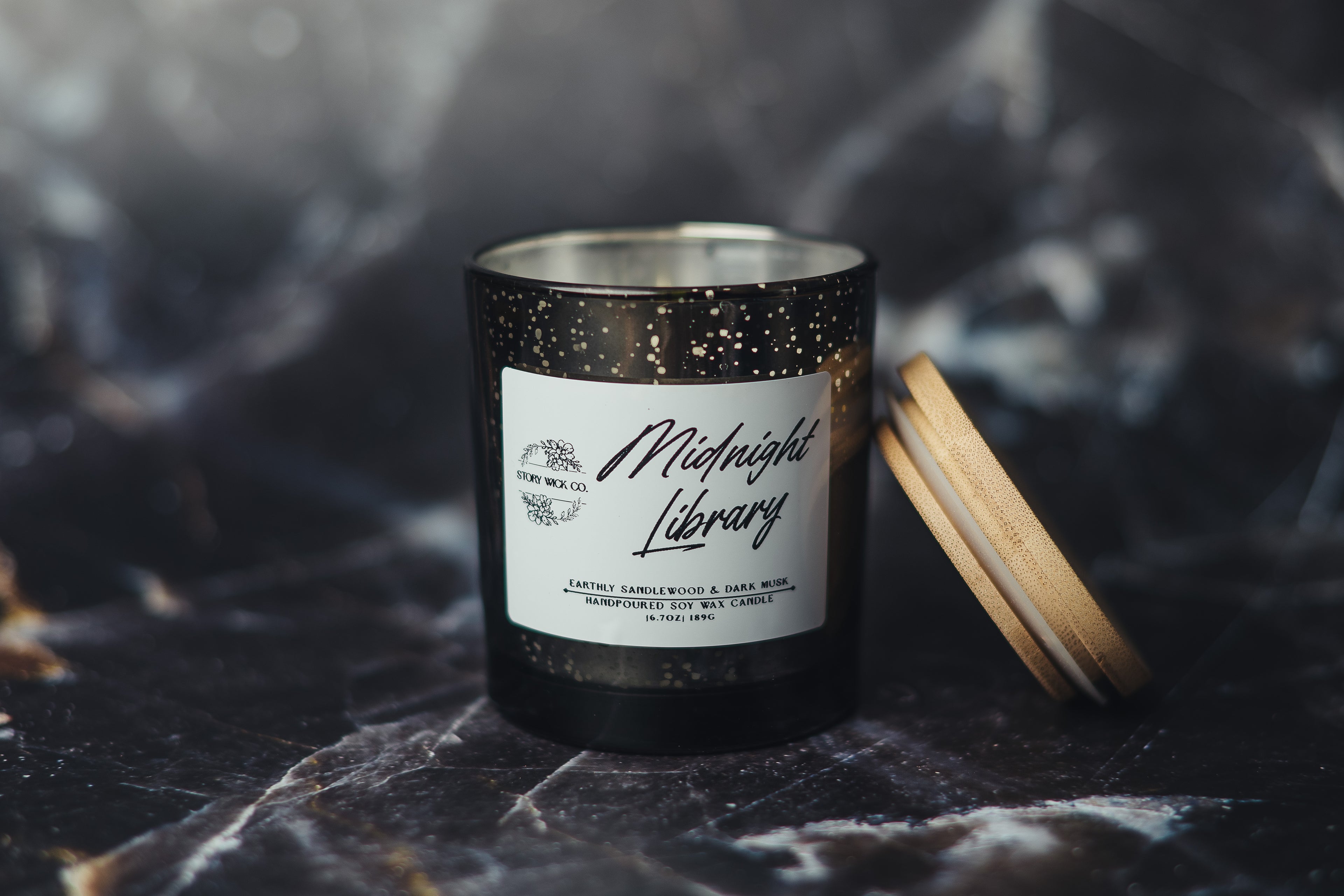 Candle with a label on a dark surface.