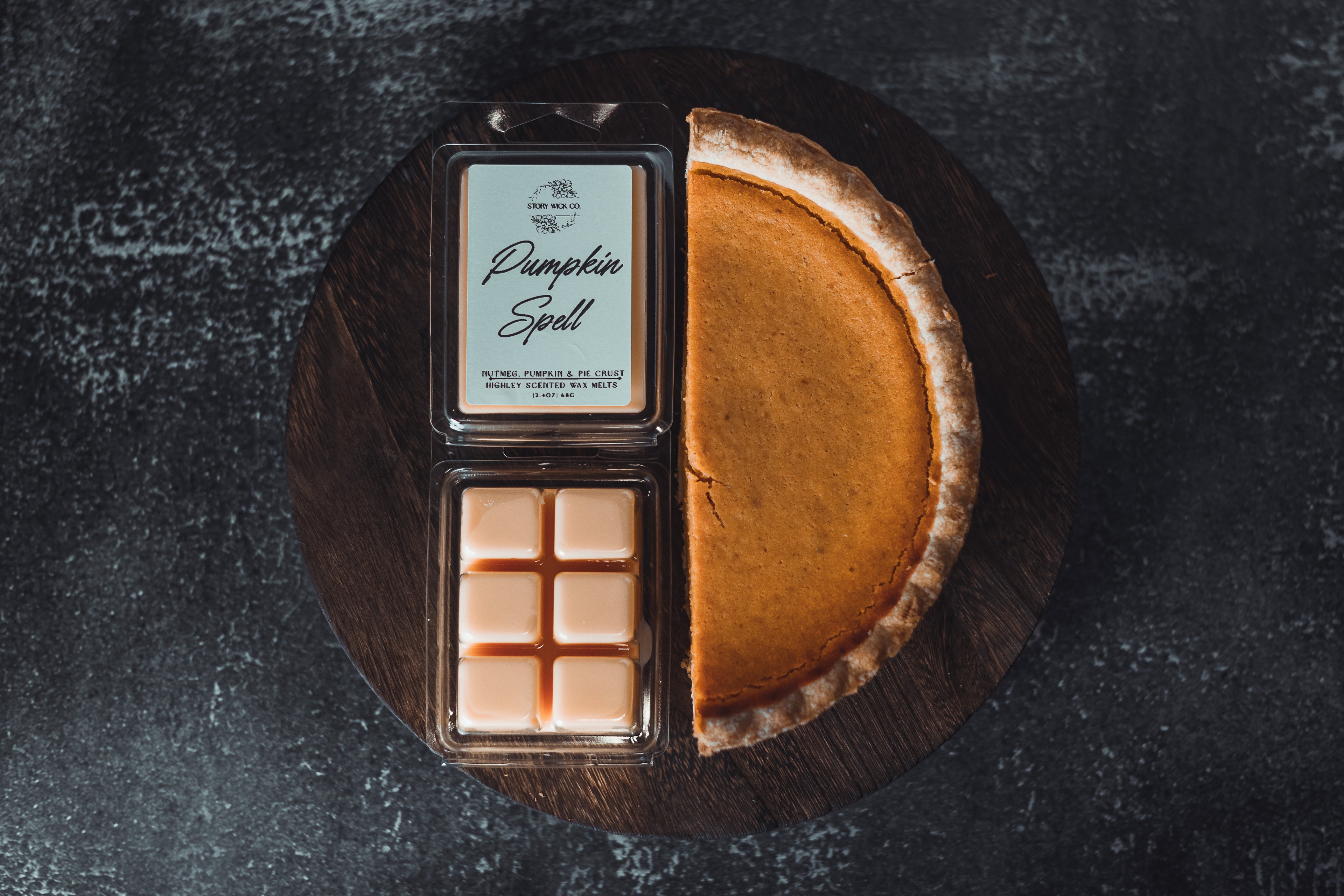 Pumpkin spell wax melt with packaging on a dark surface