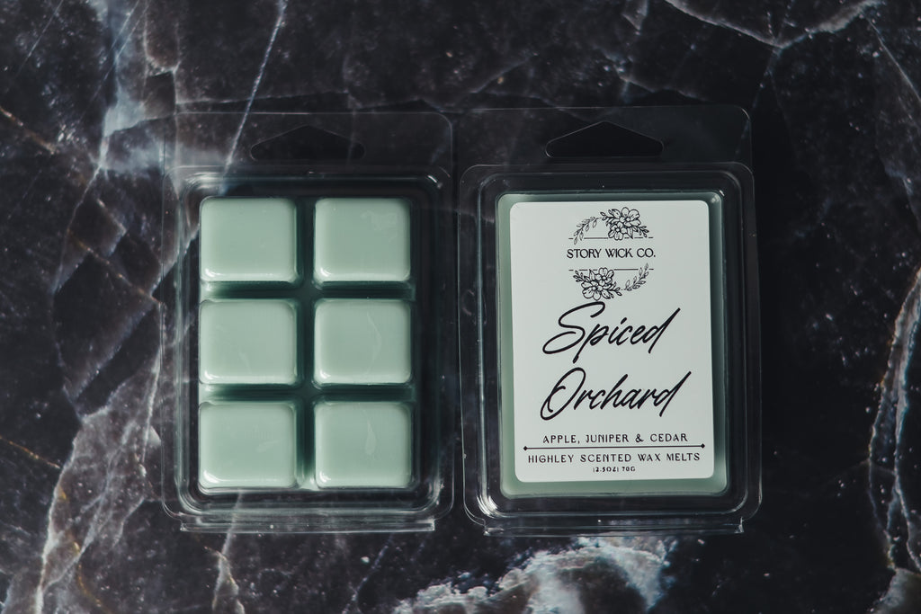 Packaged wax melts with 'Spiced Orchard' label on a dark marble surface