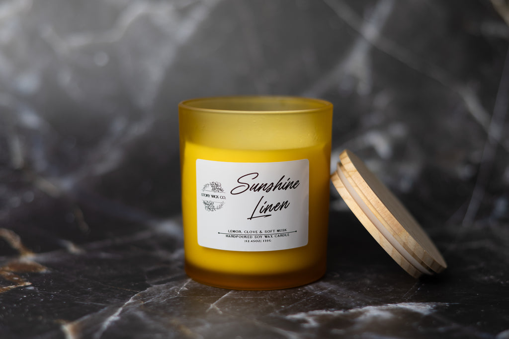 Candle labeled 'Sunshine Linen' on a dark marble surface.