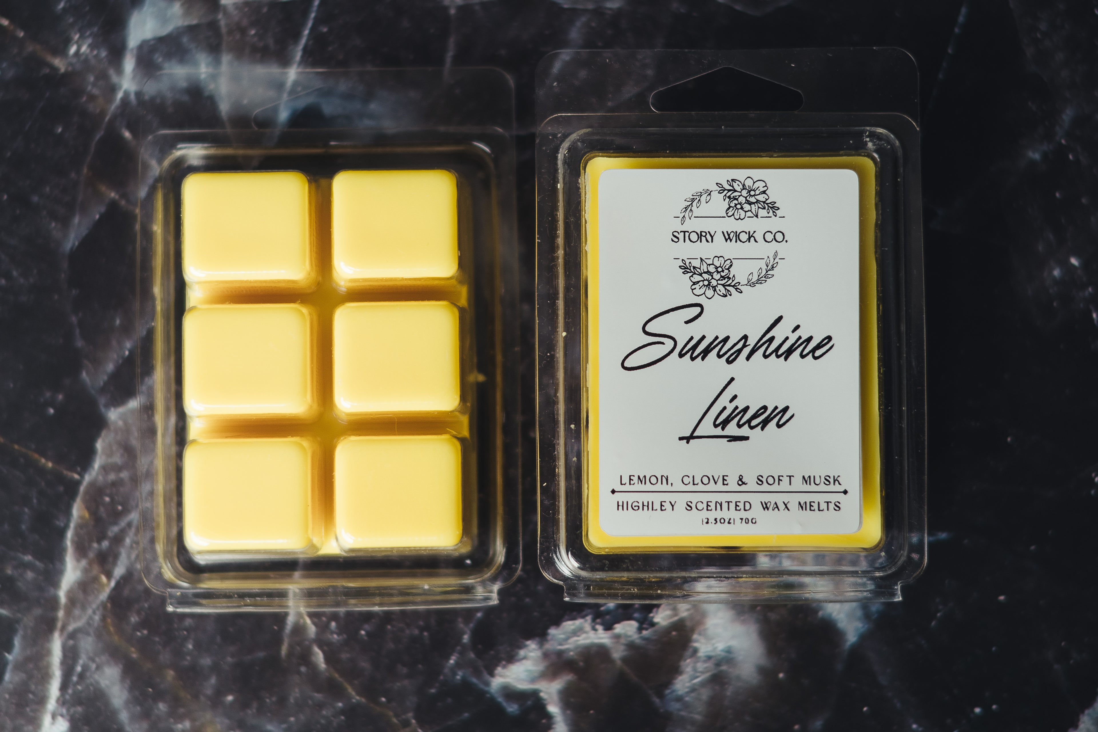 Packaged Sunshine Linen wax melts on a dark marble surface